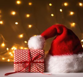 Santa Hat With A Gift Box On A Shiny Light Background