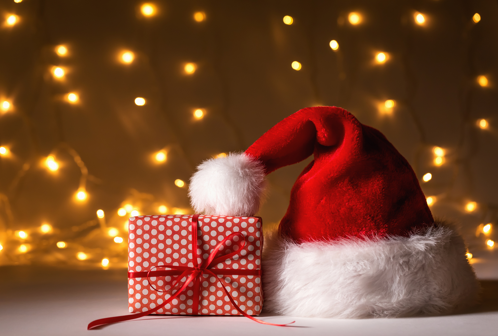 Santa Hat With A Gift Box On A Shiny Light Background